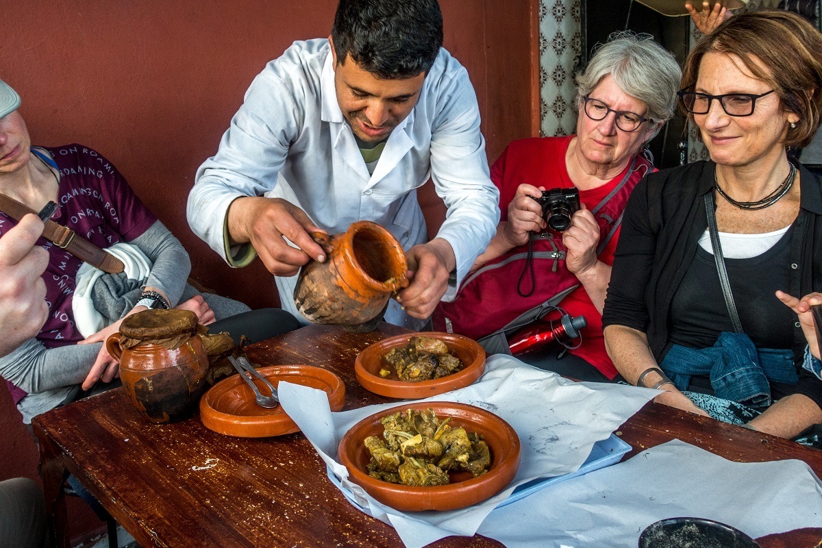 Man serving traditional Moroccan tangia meat on pottery