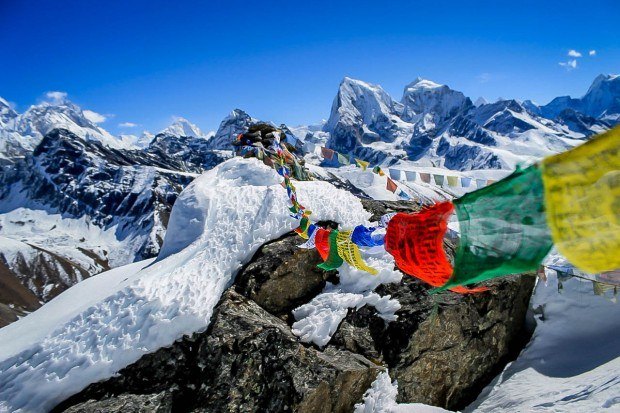 Nepalese prayer flags high in the snow covered mountains