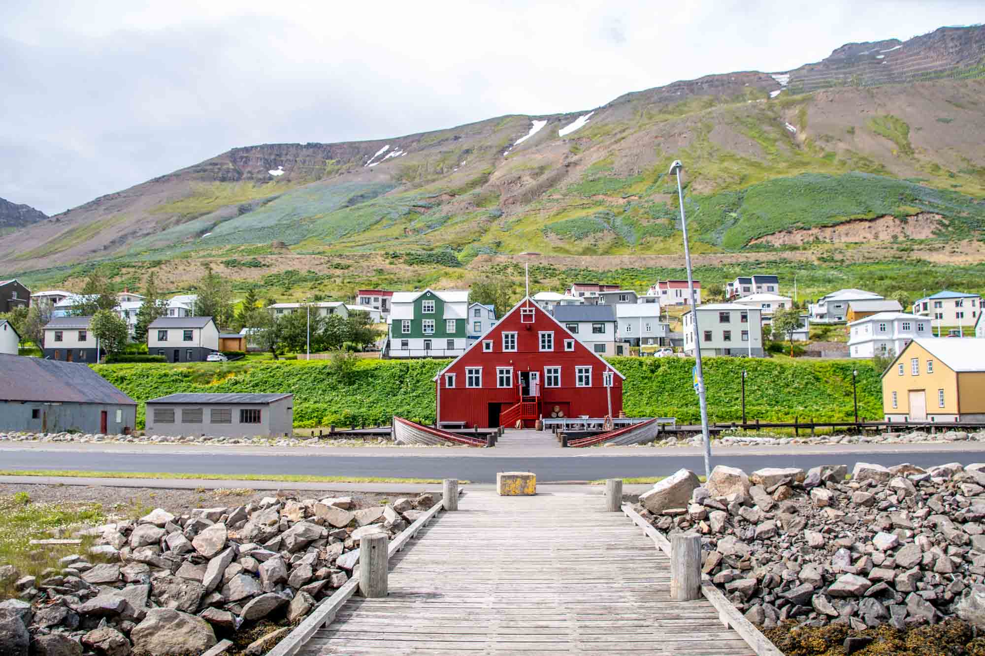 Wooden walkway leading to a red building with a mountain in the background