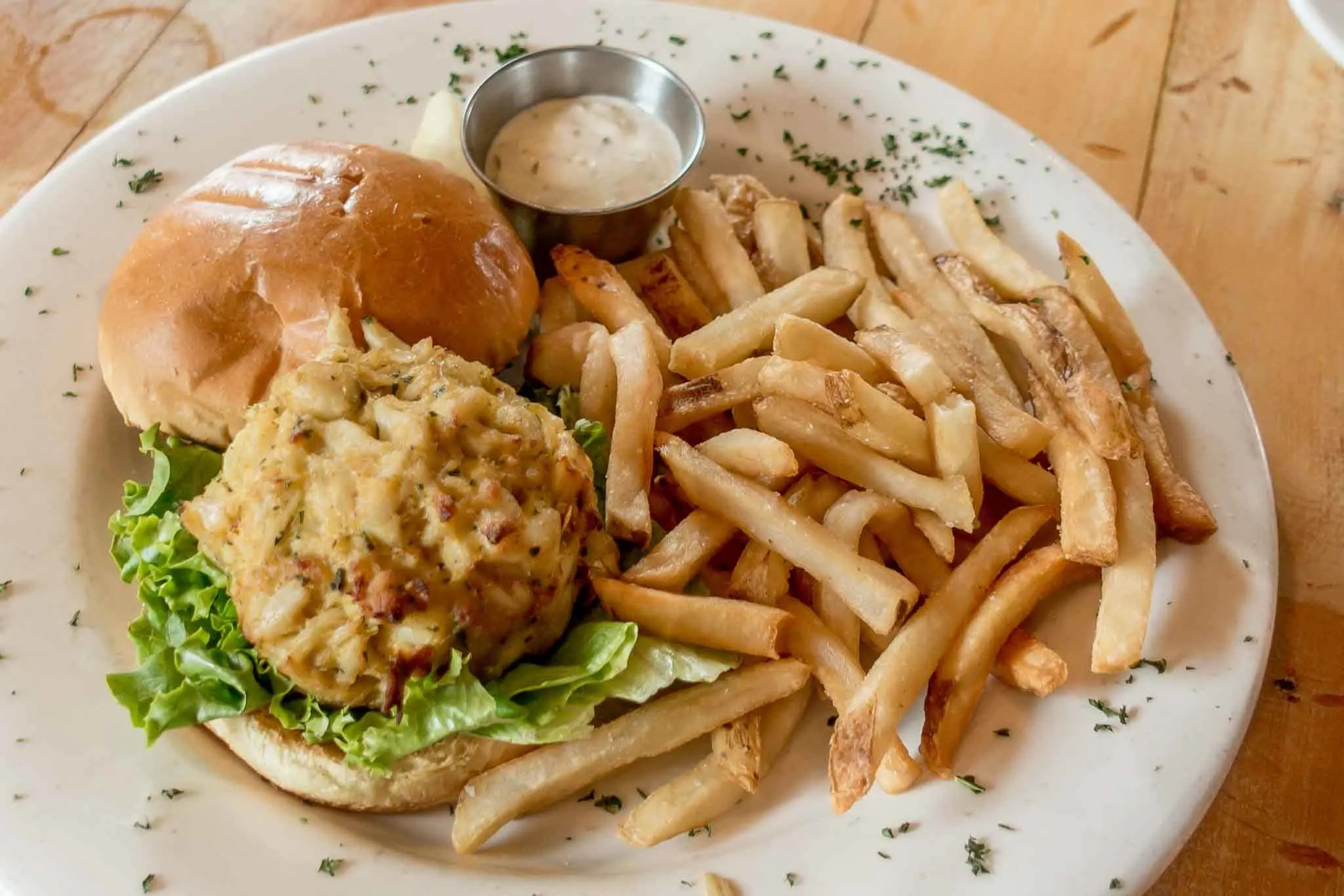 Crabcake sandwich and French fries on a plate.