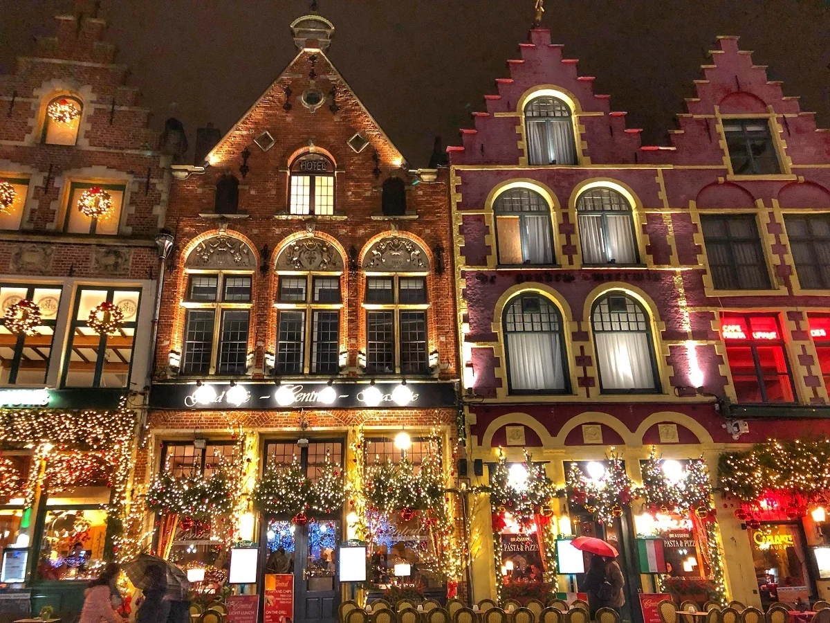 Restaurants at night lit up for Christmas on the main square of the Bruges Christmas market