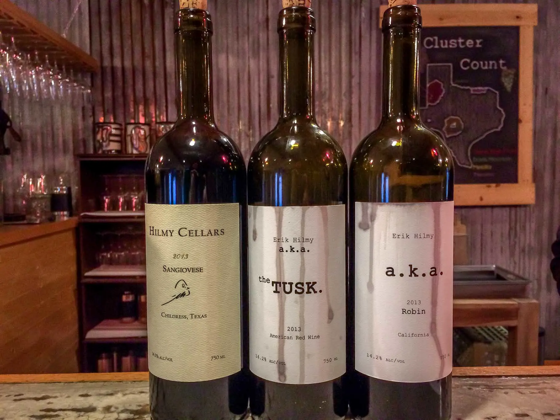 Three wine bottles on a bar