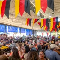 People sitting at tables under German flags at Oktoberfest in Fredericksburg
