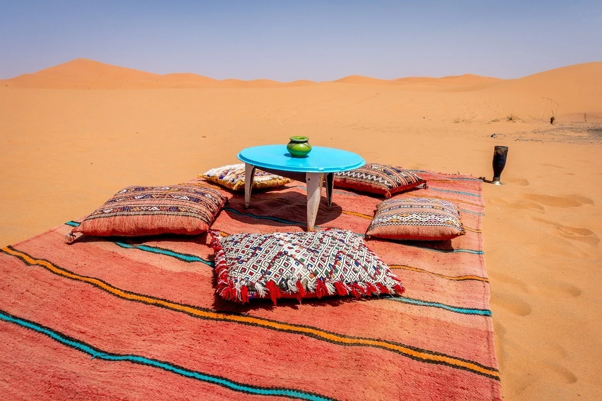 Blanket and table on sand dune in Merzouga desert of Morocco
